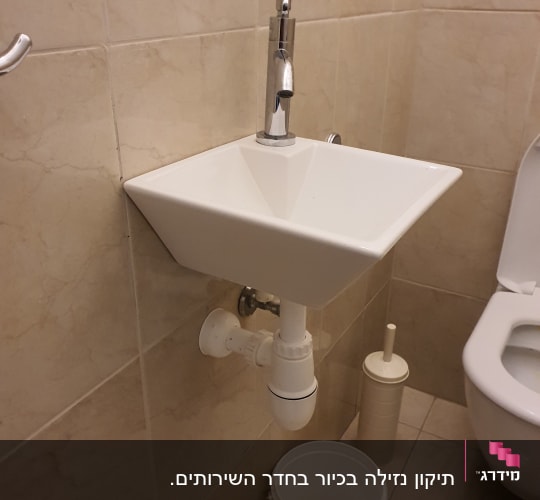 כיור עם ברז, צינור ניקוז ודלי מתחת